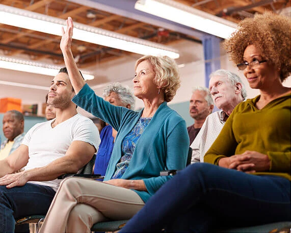 Senior woman raising her hand during an estate planning event